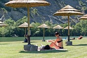 Camping La Plage Fleurie - La plage - Jeune couple allongé sur l\'herbe de la plage, en bord de rivière