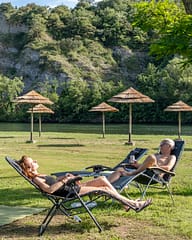 Camping La Plage Fleurie - Emplacements - Couple allong&eacute;es sur leur transat sur la plage en bord de rivi&egrave;re
