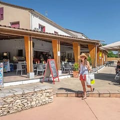Camping Arc en Ciel - Bar and restaurant - Woman leaving the grocery store and passing the restaurant terrace