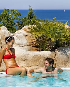Camping Le Bois de Valmarie - Espace aquatique - Couple au bord de la piscine avec vue sur La M&eacute;diterran&eacute;e