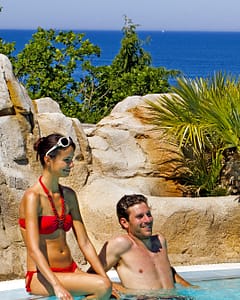 Le Bois de Valmarie campsite - Water park - Couple relaxing in the swimming pool, the Mediterranean Sea in the background