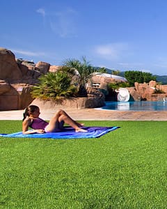 Le Bois de Valmarie campsite - Water park - Young girl lying down on the grass near the swimming pool - Sunbeds