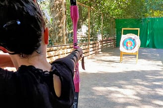 Camping Le Bois de Valmarie - Jonge vrouw die boogschieten beoefent