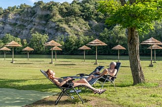 La Plage Fleurie campsite - Pitches - Couple stretched out on their sunloungers on the beach by the river
