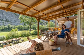 La Plage Fleurie campsite - Accommodation - Couple sitting on their cottage terrace by the Ardeche river