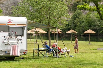 Camping La Plage Fleurie - Staanplaats aan de rivier - Stel zit op ligstoelen voor hun caravan