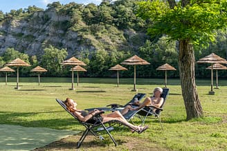 Camping La Plage Fleurie - Staanplaatsen - Stel liggend op hun ligstoel op het strand aan de rivier