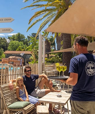 Campingplatz La Sirène - Bars und Restaurants - Mann und Tochter auf der Terrasse des Sirène Beach und Kellner mit 2 Getränken