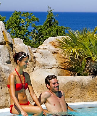 Camping Le Bois de Valmarie - Espace aquatique - Couple au bord de la piscine avec vue sur La M&eacute;diterran&eacute;e