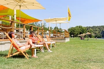 Camping La Plage Fleurie - Bar et restauration - Couple assis au River bar prenant un verre