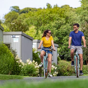 Camping Les Mouettes - Hébergements - Couple en vélo dans les allées