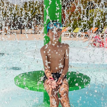 Camping Les Mouettes - Le parc aquatique - Enfant jouant sous un jet d\'eau à l\'Aqua garden